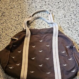 Hollister Brown Fabric with Logo. Zippered closure.